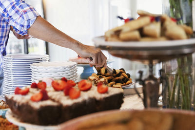 Cropped image of man arranging cookies for retail display at cafe