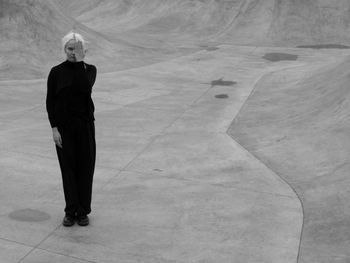 Woman in black standing on the grey concrete in monochrome 