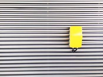 Close-up of yellow metal grate against shutter