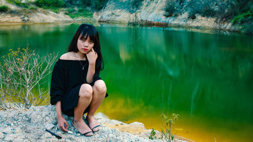 Portrait of woman sitting by lake