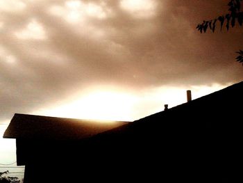 Low angle view of silhouette building against cloudy sky