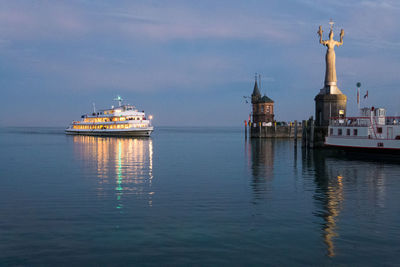 Illuminated tower by sea against sky