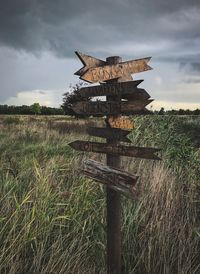 Wooden information sign on field against sky