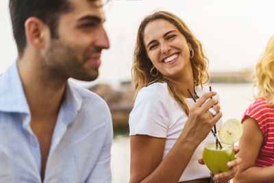 Smiling woman holding drink looking at man