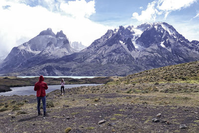 Rear view of people on snowcapped mountains against sky