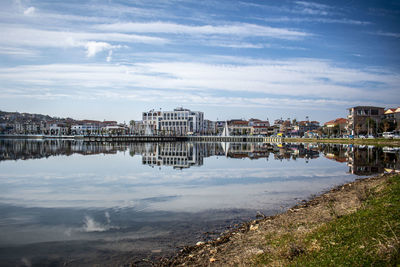Buildings by river against sky in city