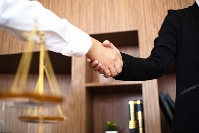 Midsection of business people shaking hand in office