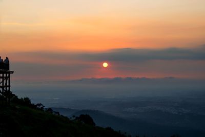 Scenic view of silhouette mountains against orange sky