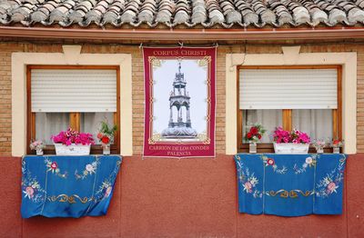 Facade with two windows decorated with flowers and sheets
