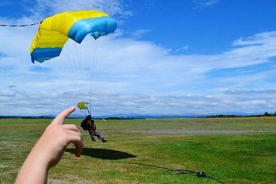 Person jumping on field against cloudy sky