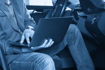 Midsection of man using laptop while sitting on sofa at home