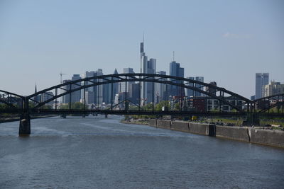 Bridge over river by buildings against sky in city