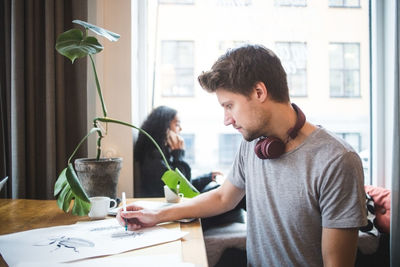 Confident male graphic designer drawing on paper at table in office