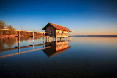 House on lake by building against blue sky