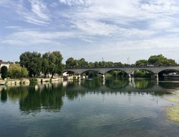 Arch bridge over river against sky