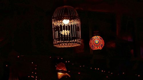 Low angle view of illuminated light bulbs hanging at night