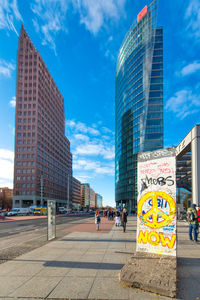 City street by modern buildings against sky