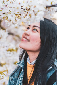 Smiling young woman looking at blooming flowers