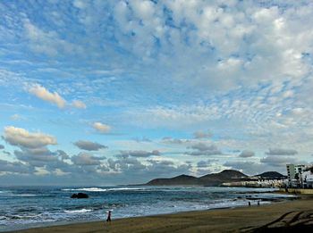 Scenic view of beach against cloudy sky