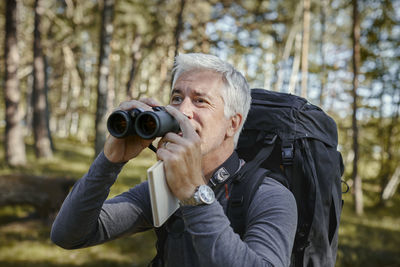 Midsection of man holding camera in forest