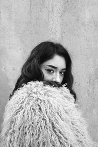 Portrait of young woman against wall