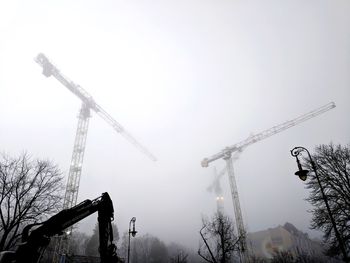 Low angle view of cranes against sky