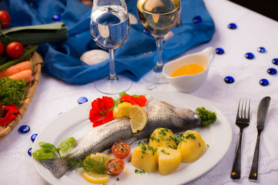 High angle view of fish with wine and salad served on table in restaurant