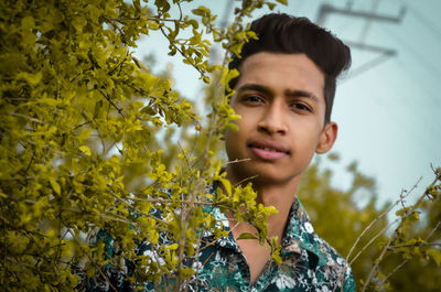 Portrait of smiling man against plant outdoors