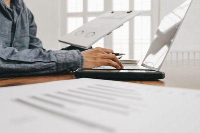 Midsection of businessman using laptop on desk in office