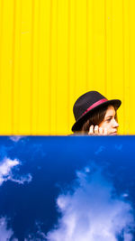 Portrait of woman wearing hat against yellow wall