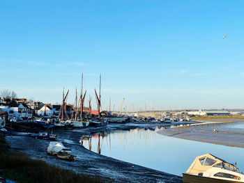 Sailboats moored at harbor against sky