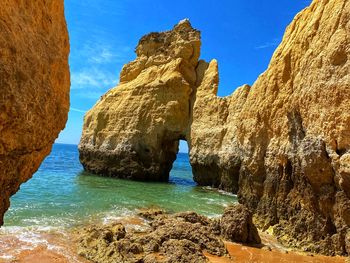 Rock formations by sea against blue sky