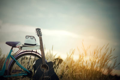 Bicycle on field against sky during sunset