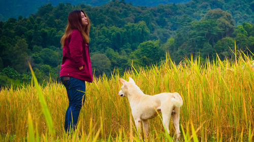 Woman with dog standing on field