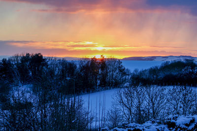 Scenic view of snow covered land against sky during sunset