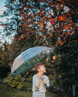 Full length of boy standing by tree during rainy season