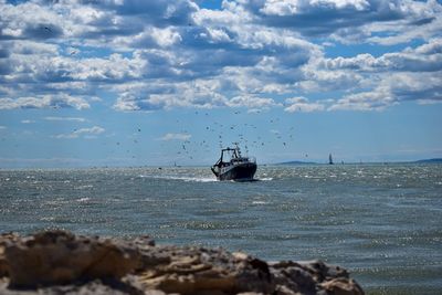 Fishing boat on sea against sky