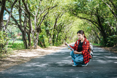 Full length of man sitting on road in forest