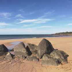 Rocks at beach against sky