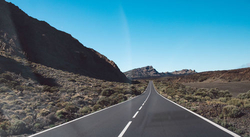 Empty road along landscape and mountains against sky