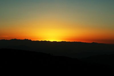 Scenic view of silhouette mountains against clear sky during sunset