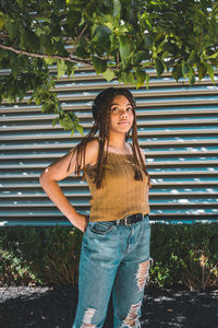 Portrait of young woman standing against tree