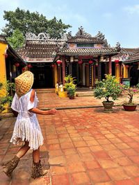 Rear view of woman walking on footpath by house