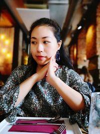 Portrait of young woman sitting in restaurant
