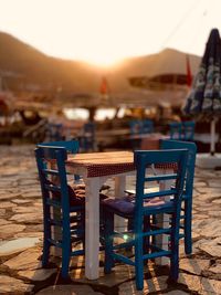 Empty chairs and tables at beach against sky