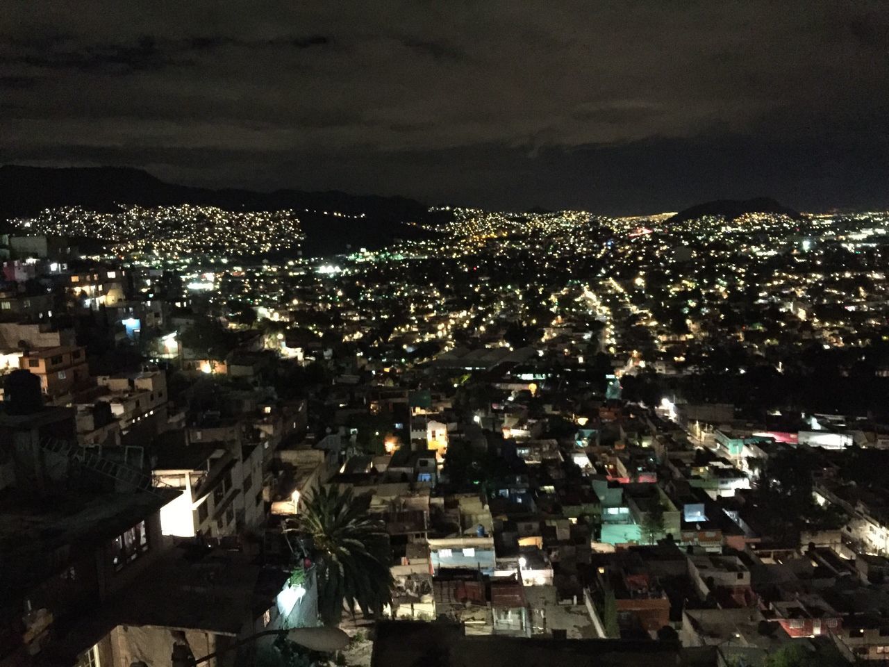 HIGH ANGLE VIEW OF ILLUMINATED CITY AGAINST CLOUDY SKY