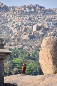 Rear view of people sitting on rock against mountain