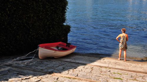 Rear view of woman standing by lake orta