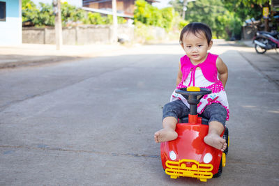 Portrait of cute girl sitting on road