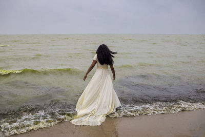 Rear view of woman on beach against sky